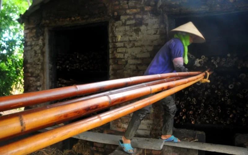 Người thợ đưa tre ra khỏi lò hun khói